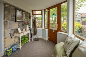 A cozy room with a stone wall, a wooden door, and a view of the outside.