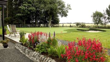 A golf course with a stone border, chairs, and potted plants.