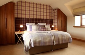 A bedroom with a large bed, wooden wardrobe, and a window with a view.