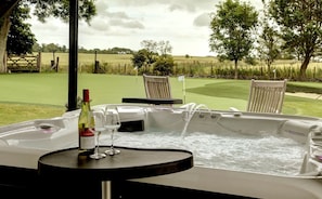 A hot tub with a table and chairs, a bottle of wine, and a glass.