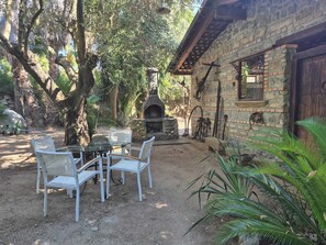 An outdoor patio with a stone building, a brick oven, and a table with chairs. - A Wonderful Villa Surrounded by Lush Greenery, Peacefully Located Near the Beach (Calabria)
