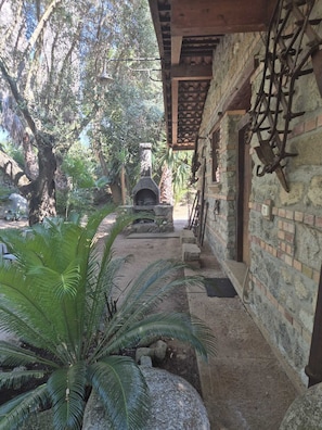 A courtyard with a stone oven, a brick wall, and a wooden pergola.