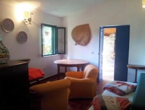 A room with a bed, a chair, a table, and a window.