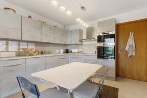 A modern kitchen with a central island, built-in appliances, and a wooden door. - “Saint Raphael De Luxe” Apartment with Shared Pool and Private Terrace (Saint-Raphaël)