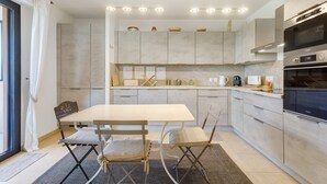 Una cocina moderna con una isla central, electrodomésticos integrados y una zona de comedor con sillas plegables.