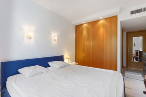 A hotel room with a large bed, two wall-mounted lights, a wooden wardrobe, and a mirror. - “Saint Raphael De Luxe” Apartment with Shared Pool and Private Terrace (Saint-Raphaël)