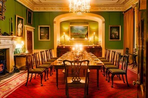 Un comedor formal con una larga mesa, sillas, una chimenea y obras de arte enmarcadas en las paredes.