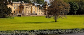 A large, classical building with a symmetrical facade, a prominent clock tower, and a well-manicured lawn in front.