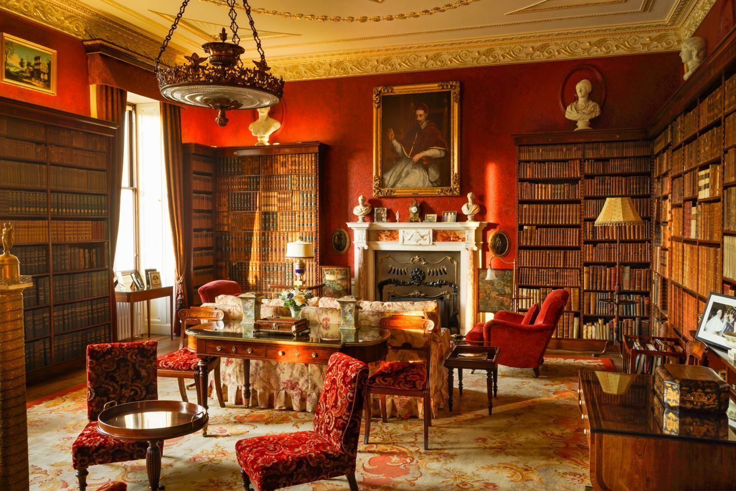 A library with bookshelves, a fireplace, and a red armchair.