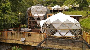 Estructuras de domos geodésicos con asientos exteriores y una terraza de madera.