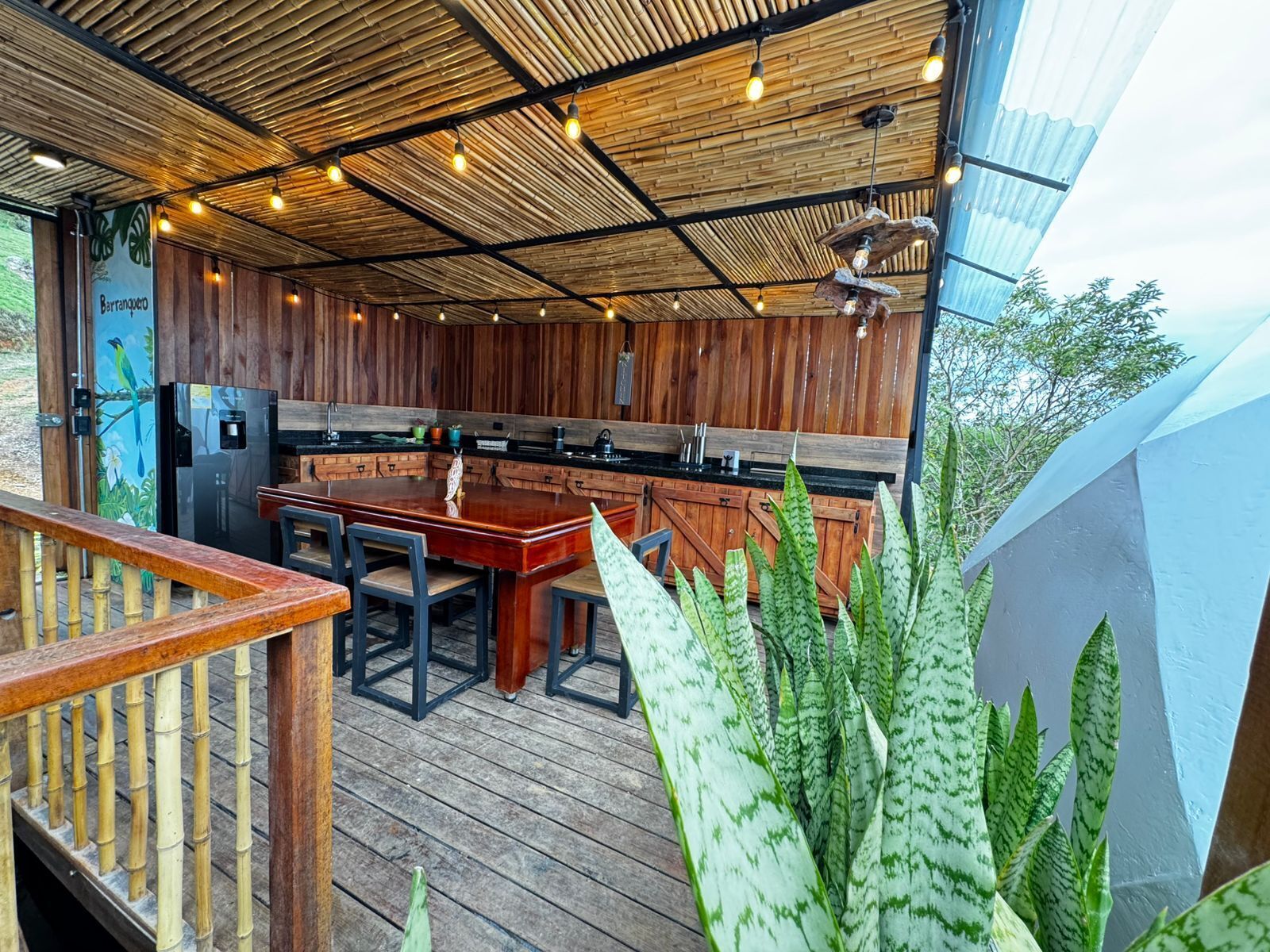 Un espace cuisine extérieur doté d’une terrasse en bois, d’une table à manger et de chaises.