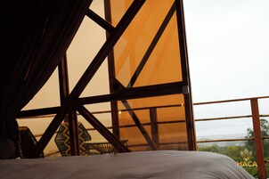 Una habitación con una cama, una mesa y sillas, y vistas al exterior a través de ventanas amplias.
