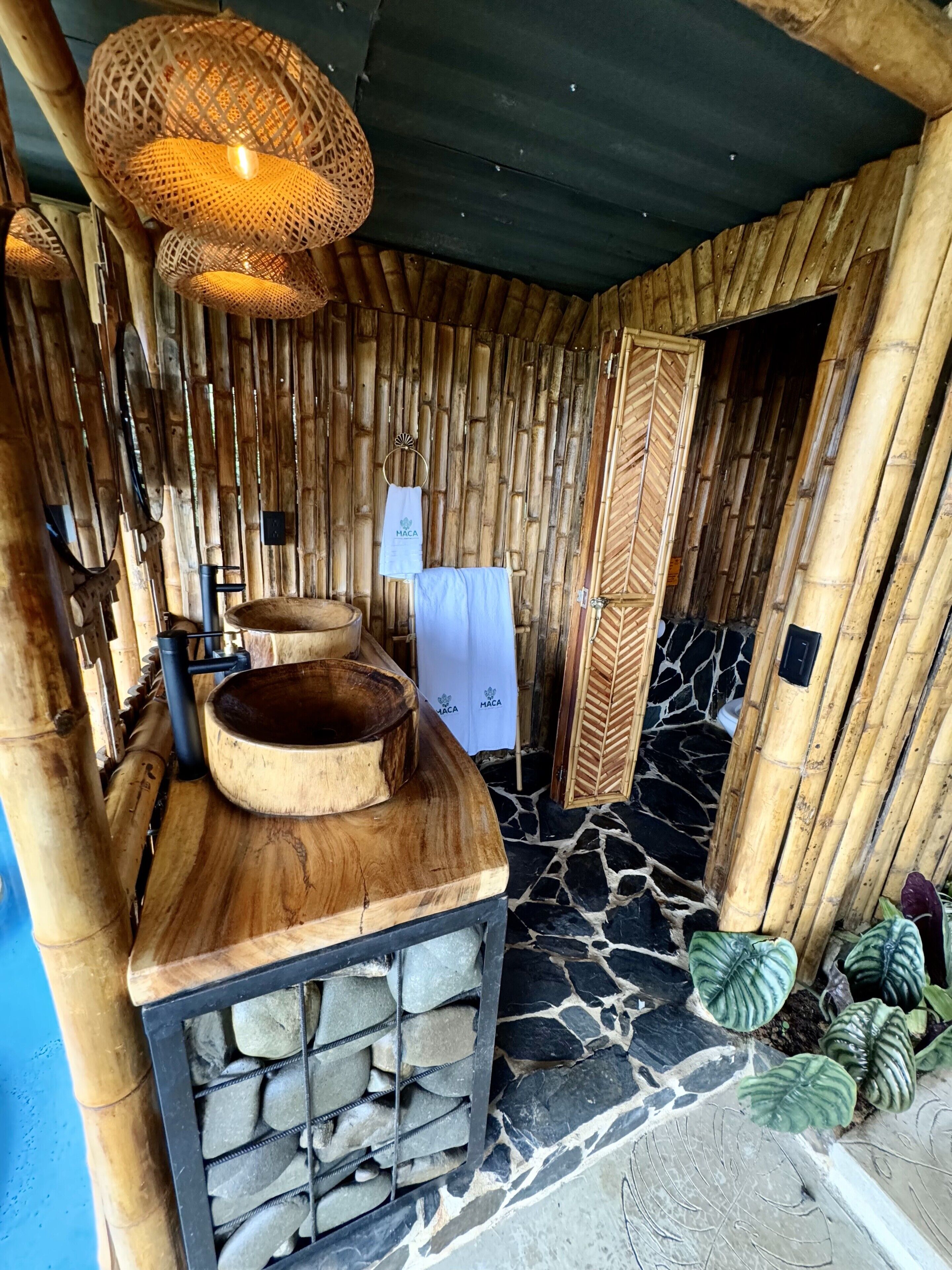 Een badkamer met een houten wastafelmeubel, een stenen wastafel en een bamboe wand.