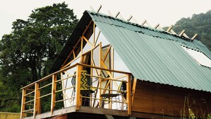 Una cabaña de madera con balcón, rodeada de árboles.