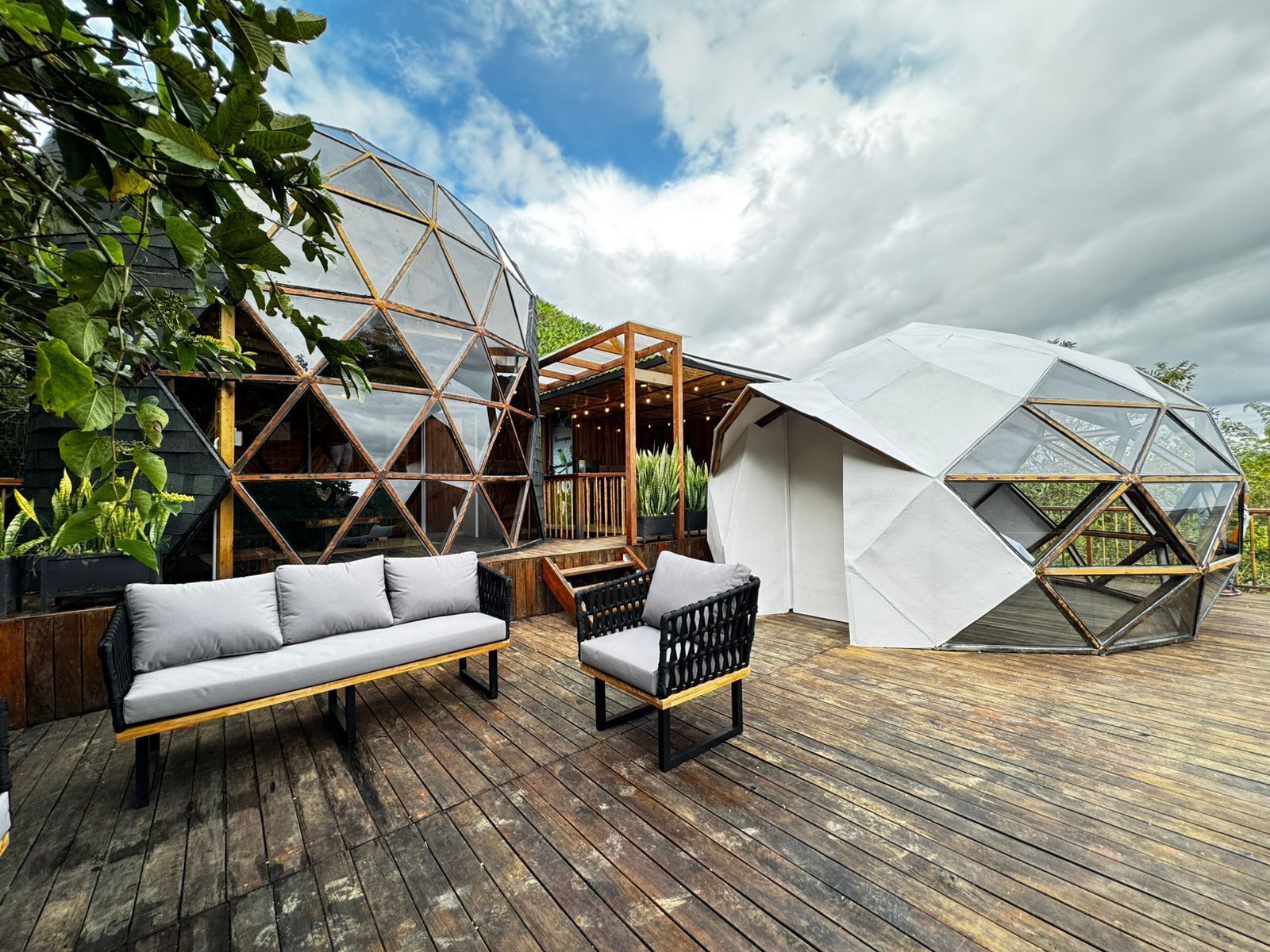 A modern outdoor seating area with a wooden deck, two sofas, and a bench.