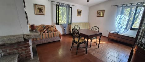 A dining area with a table and chairs, a sofa, and a staircase.