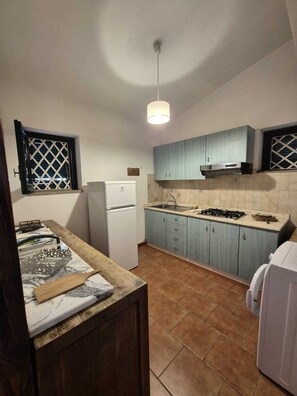A compact kitchen with a refrigerator, stove, and blue cabinets. - Wonderful Villa Surrounded by Lush Greenery - Peaceful Location Near the Beach (Calabria)