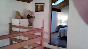 A room with a wooden staircase, a bed with a checkered bedspread, a nightstand with a lamp, and a painting on the wall. - Holiday Home 'Gite Des Carcis' with Mountain View, Private Terrace and Wi-Fi (Ganac)