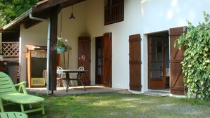 A patio with a table and chairs, a hanging flower pot, and a wooden door. - Holiday Home 'Gite Des Carcis' with Mountain View, Private Terrace and Wi-Fi (Ganac)