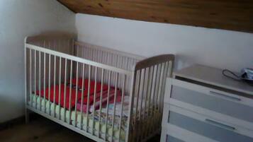 Een kamer met een ledikant, een dressoir en een schuine plafond.