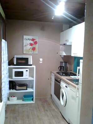 A compact kitchen with a microwave, oven, and washing machine. - Holiday Home 'Gite Des Carcis' with Mountain View, Private Terrace and Wi-Fi (Ganac)