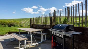 An outdoor patio with a barbecue grill and picnic tables.