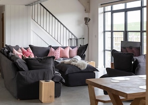 A modern living room with a black sofa, a wooden coffee table, and a staircase with a metal railing.