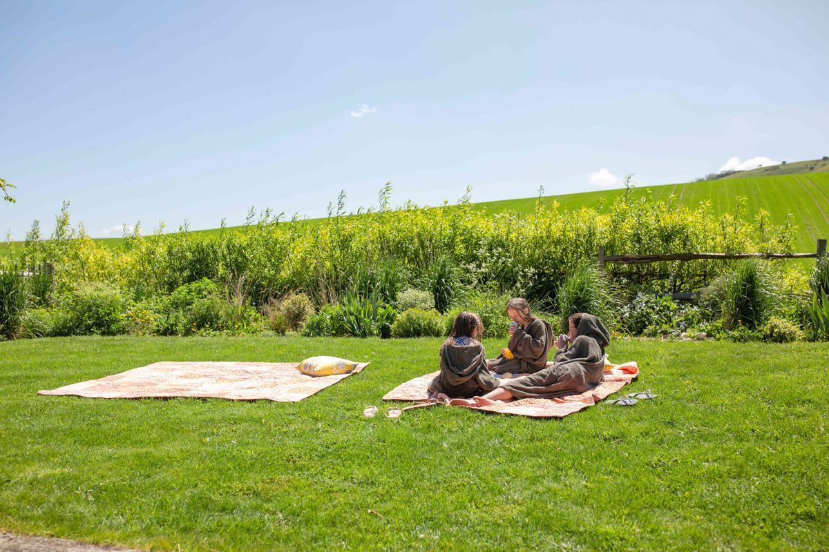 A grassy outdoor area with people sitting on blankets.