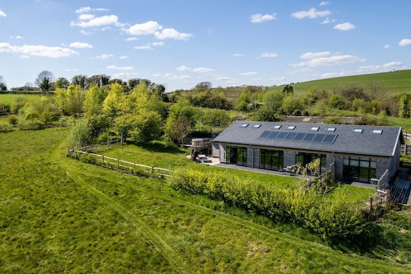 A modern house with a sloped roof, solar panels, and a large glass window.