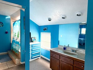 Un bagno con una parete blu, un lavandino bianco e un armadietto in legno.
