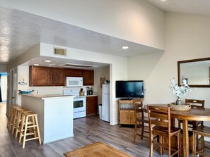 A modern kitchen with wooden cabinets, a microwave, and a dining area with a wooden table and chairs. - Romantic of family convenient (Willis)