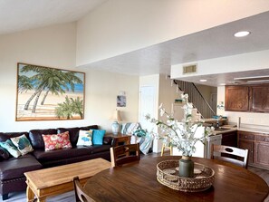 A living room with a dark leather sofa, a wooden coffee table, and a painting of a beach scene. - Romantic of family convenient (Willis)