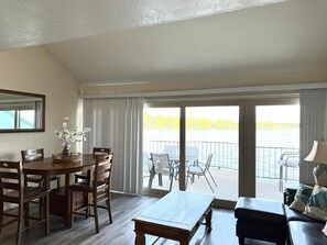 A room with a dining table, chairs, a sofa, and a view of a body of water through large windows. - Romantic of family convenient (Willis)