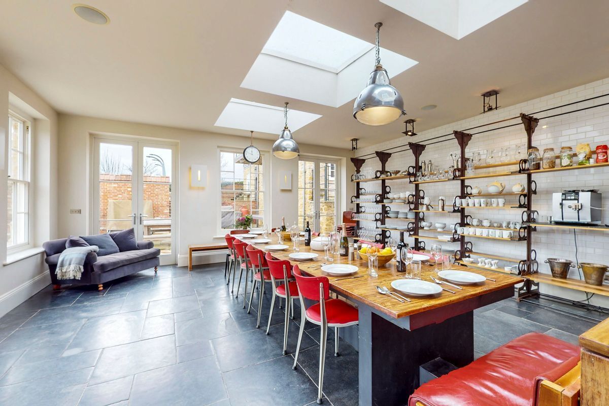 A modern kitchen with a central island, red chairs, and a dining table set for six.