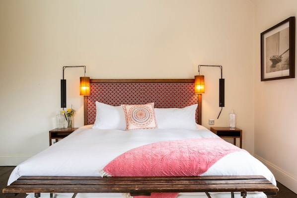 A neatly made bed with a wooden headboard, two bedside lamps, and a framed picture on the wall.