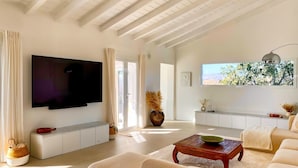 Un soggiorno moderno con una TV a schermo piatto, una grande finestra con vista e un'accogliente area salotto.