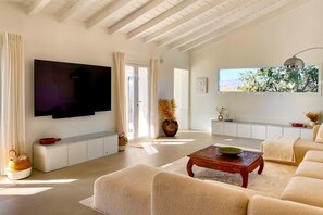 Ein modernes Wohnzimmer mit Flachbildfernseher, großem Fenster und schöner Aussicht sowie einer gemütlichen Sitzecke.