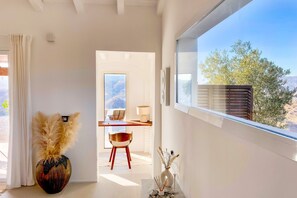 Ein modernes Interieur mit einem großen Fenster, einem Holztisch, einem Stuhl und einer dekorativen Vase.