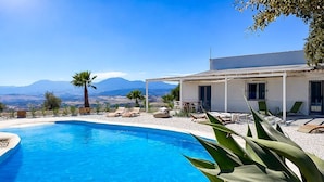 Una piscina con lettini e vista sulle montagne.