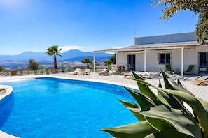Ein Pool mit Liegestühlen und Blick auf Berge.