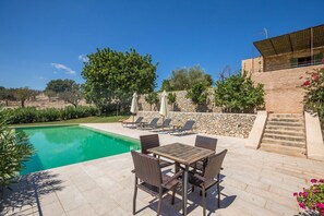 A poolside area with a table and chairs, a stone wall, and a staircase leading to a building. - Casa Begura - Two Bedroom Villa, Sleeps 4 (Mallorca)