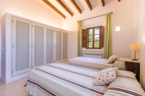 A bedroom with a bed, a nightstand, a lamp, a window with curtains, and a wardrobe. - Casa Begura - Two Bedroom Villa, Sleeps 4 (Mallorca)