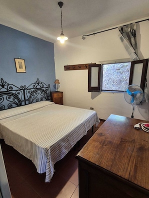 A bedroom with a bed, bedside table, lamp, window, and a ceiling fan. - A wonderful villa surrounded by lush greenery, peacefully located near the beach (Calabria)
