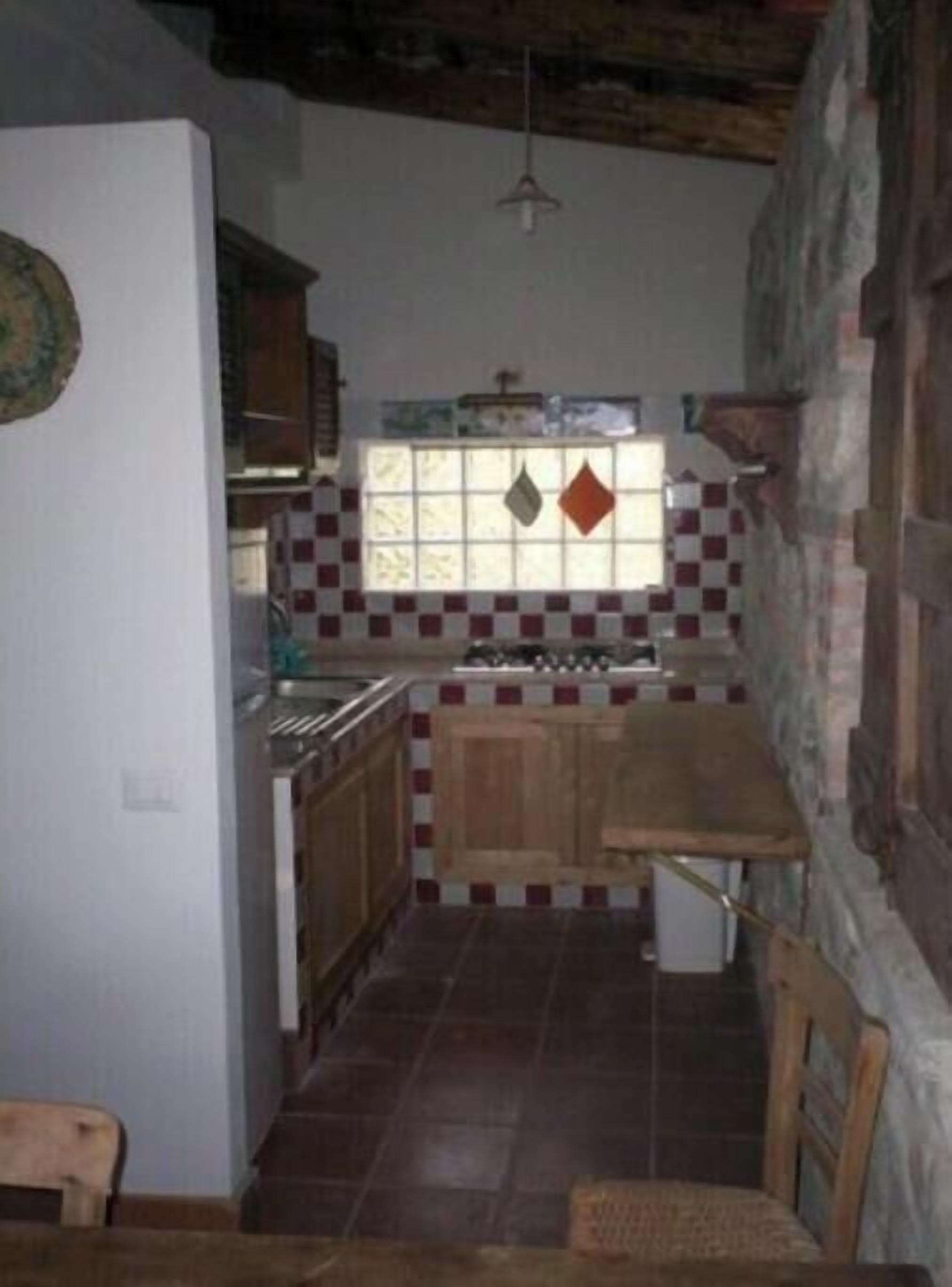 Una cocina compacta con un salpicadero a cuadros, armarios de madera y piso de baldosas.