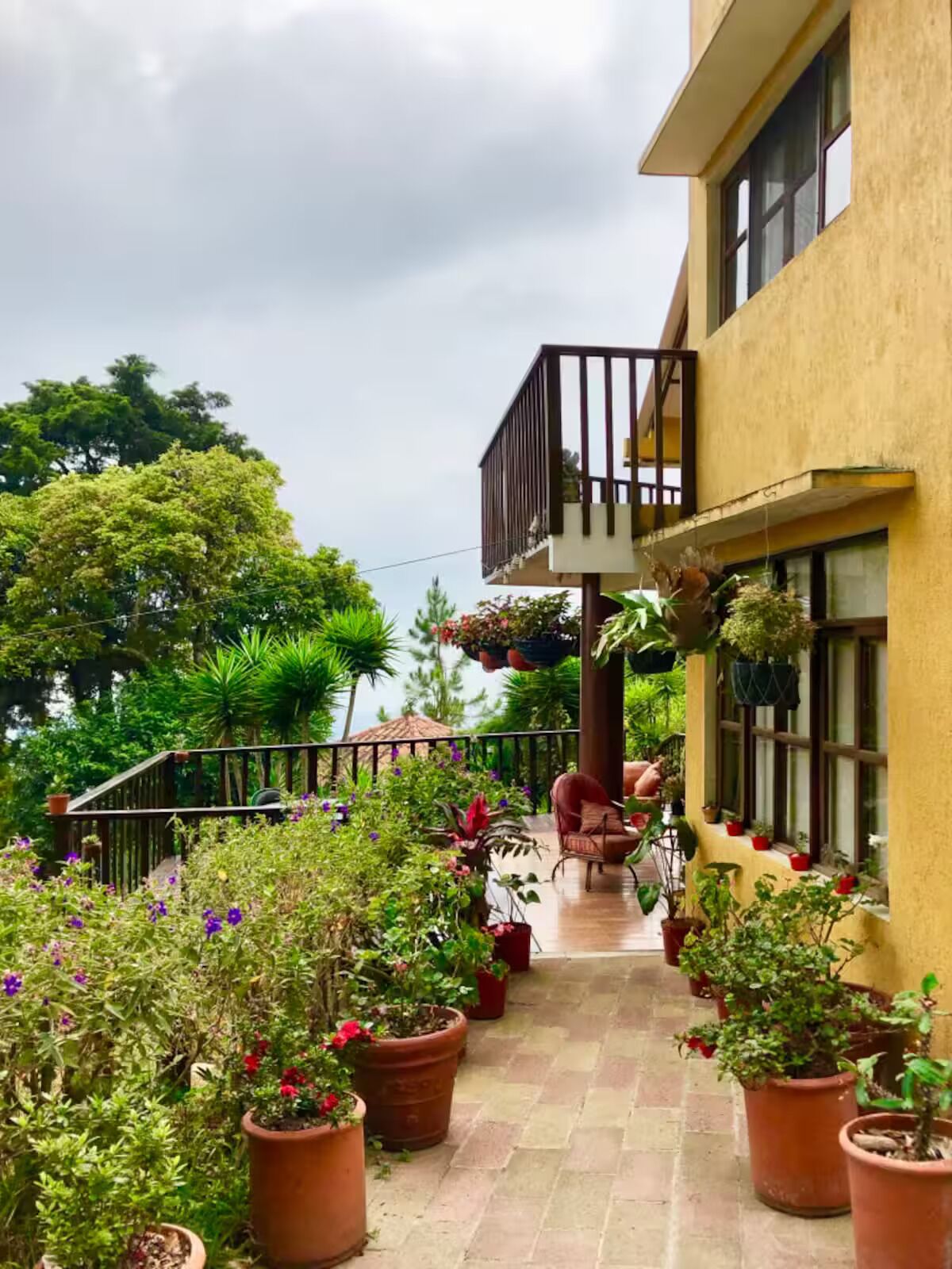 Un immeuble doté d’un balcon, de plantes en pot et d’un escalier menant à un étage supérieur.