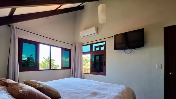 Een slaapkamer met een bed, een televisie en ramen.