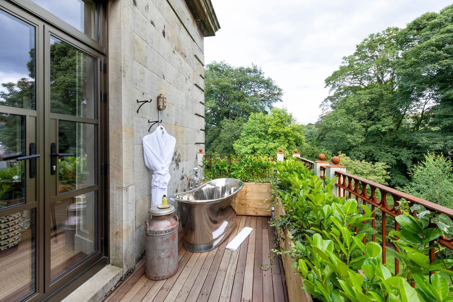 A wooden deck with a spa tub, a white robe, and a metal container labeled 'East Kilbride.'
