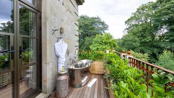 A wooden deck with a spa tub, a white robe, and a metal container labeled 'East Kilbride.'