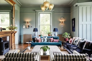 A living room with a fireplace, two sofas, a coffee table, and a chandelier.