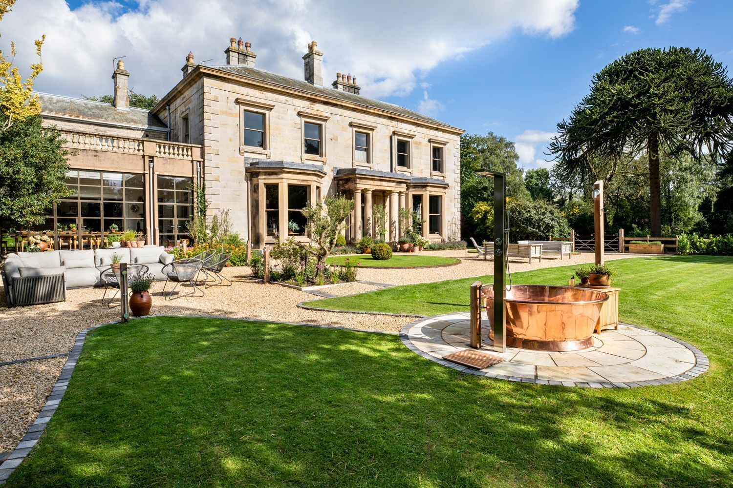 A large, two-story stone building with a well-maintained lawn and a hot tub in the center.